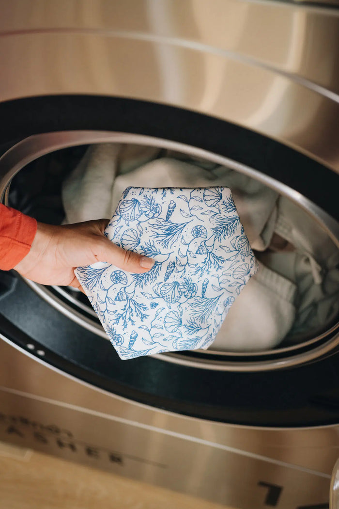 Hand placing the Sea Floor Hexawash pouch in the drum