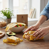SuperBee Australia beeswax wraps with alpaca print covering a loaf of bread and a bowl of salad on a wooden table.
