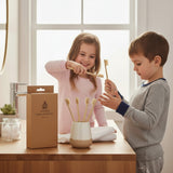 SuperBee Australia bamboo toothbrushes in a holder with two children brushing their teeth in a bright bathroom