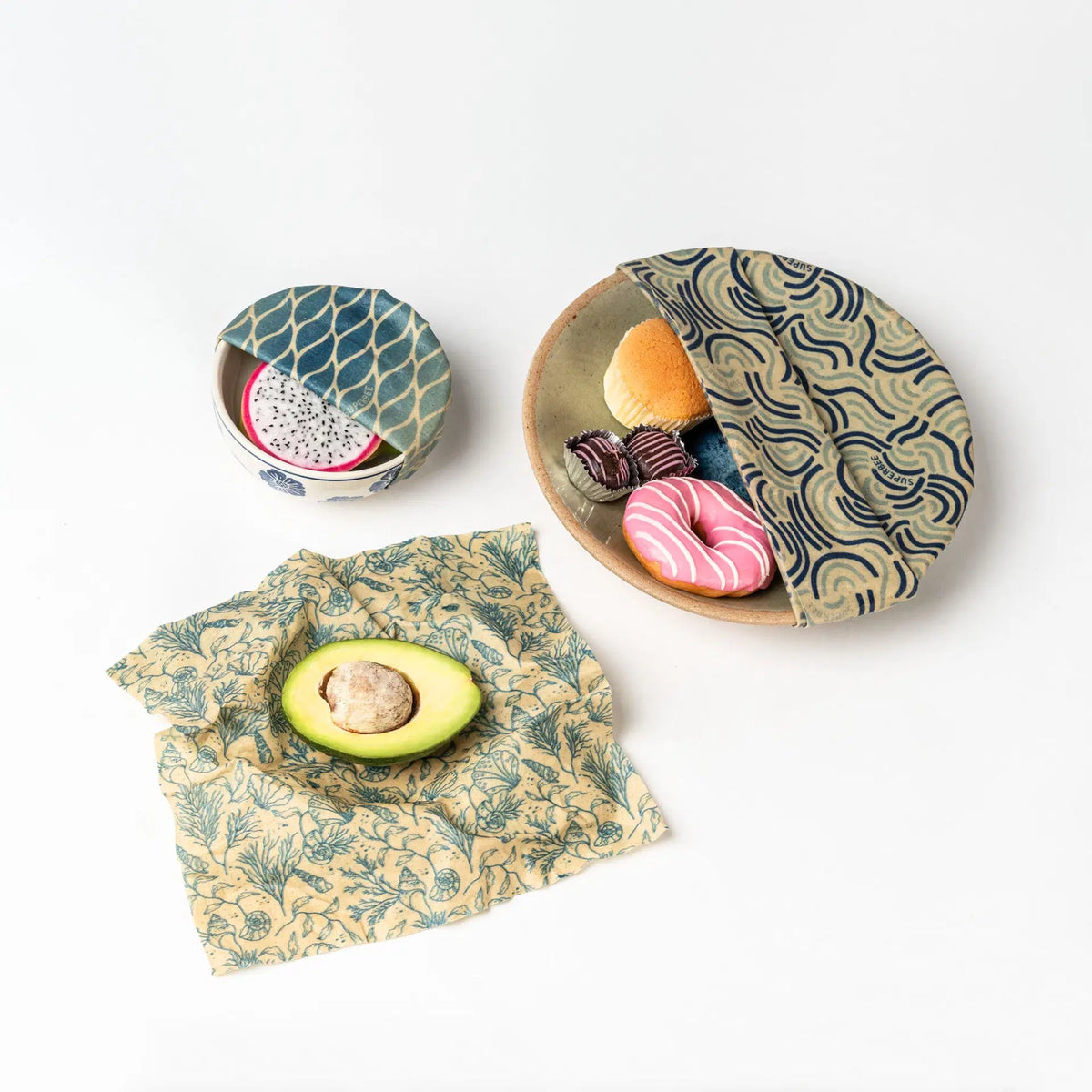 SuperBee Australia beeswax wrap set with ocean-themed patterns covering bowls of fruit, pastries, and an avocado.