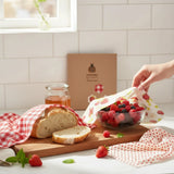 SuperBee Australia beeswax wrap set with strawberry and red gingham patterns covering bread and a bowl of berries.