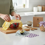SuperBee Australia beeswax wraps in zig zag patterns covering a bowl of berries and an avocado on a kitchen counter.