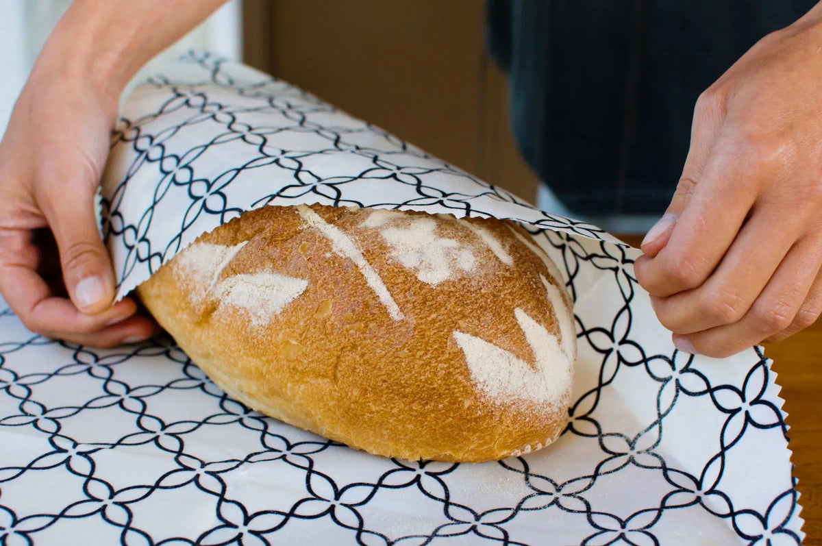 SuperBee Australia extra large beeswax wrap with a black and white meadow pattern wrapping a loaf of crusty bread