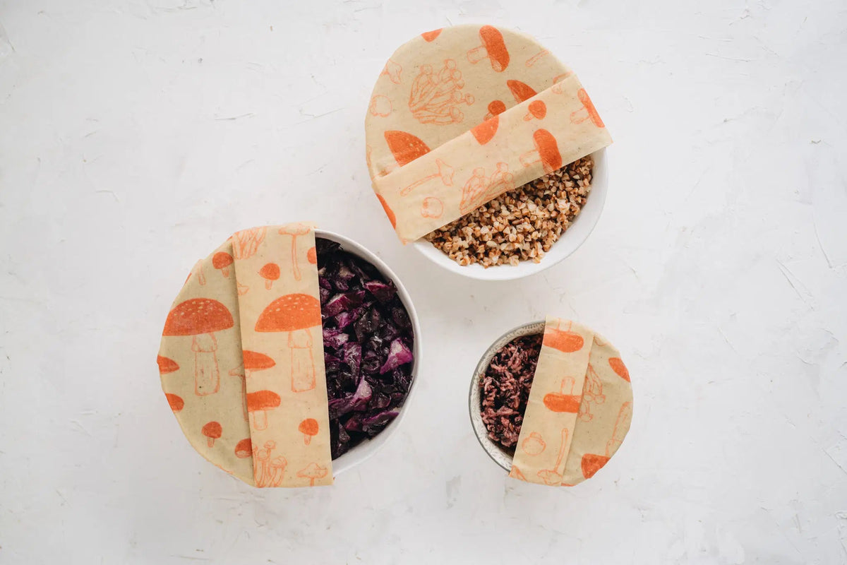 SuperBee Australia beeswax wrap roll with orange mushroom print covering three bowls of food on a white background