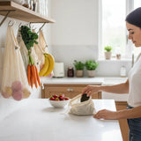 SuperBee Australia organic cotton mesh produce bags hanging in a kitchen with a woman placing an avocado in one.