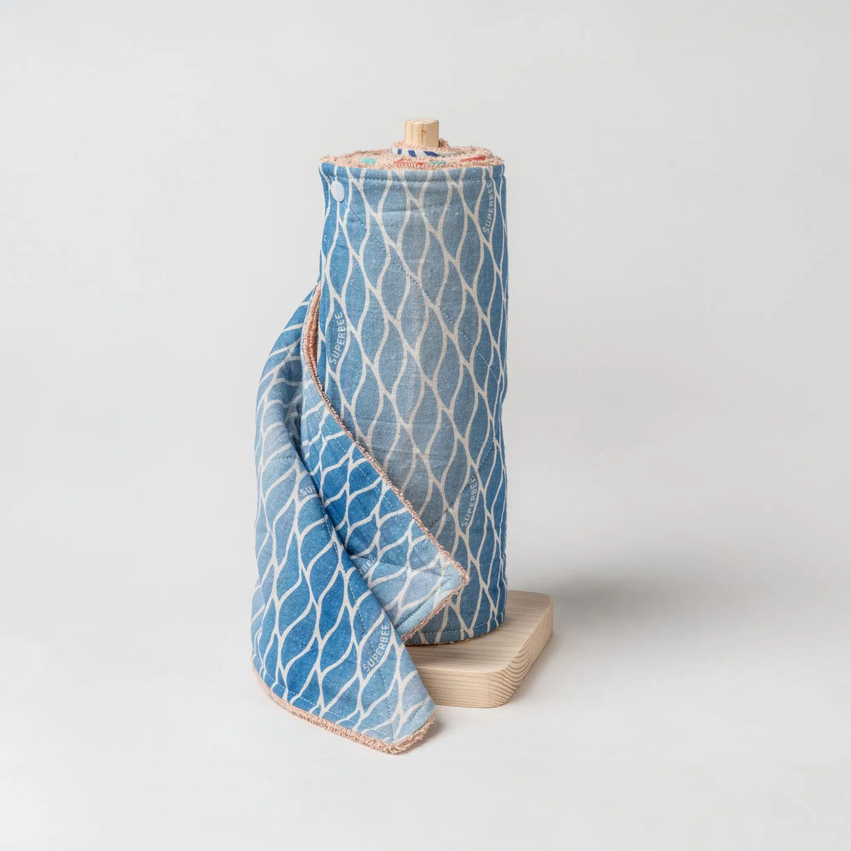 SuperBee Australia reusable paper towel roll in Blue Lagoon organic cotton with a geometric pattern on a wooden stand