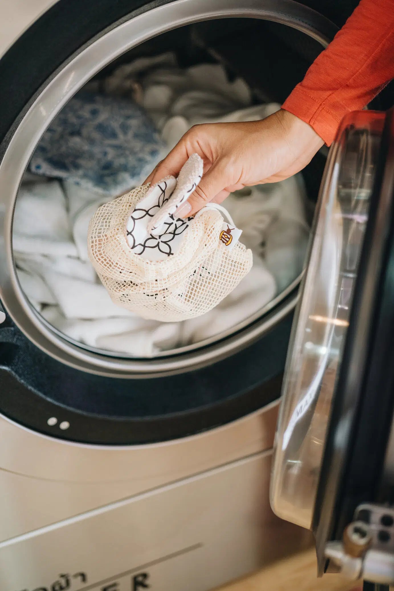 SuperBee Australia reusable makeup remover pads in a mesh laundry bag being placed into a washing machine