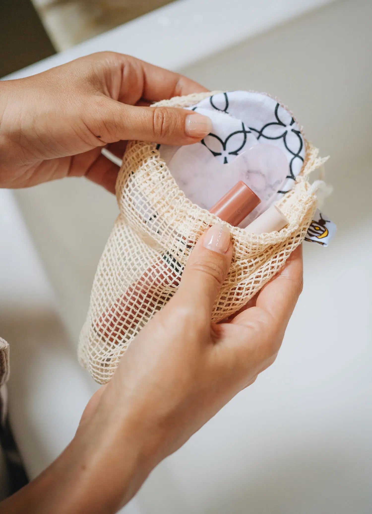 SuperBee Australia reusable makeup remover pads in a mesh laundry bag with a patterned design and skincare tools
